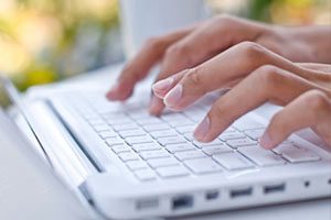 Close View of Woman's Hands Typing on a White Laptop