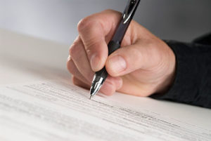 Man's Hand Holding a Nice Pen and Signing Paperwork