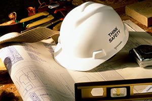 White Hard Hat Reading 'Think Safety' Sits on Top of Construction Blueprints