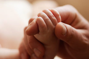 Close Shot of a Parent Holding Their Tiny Newborn's Hand Between Two Fingers