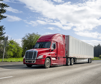 Red semi truck driving down a freeway