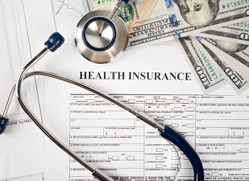 A form with the title Health Insurance and a stethascope and several hundred dollar bills on top