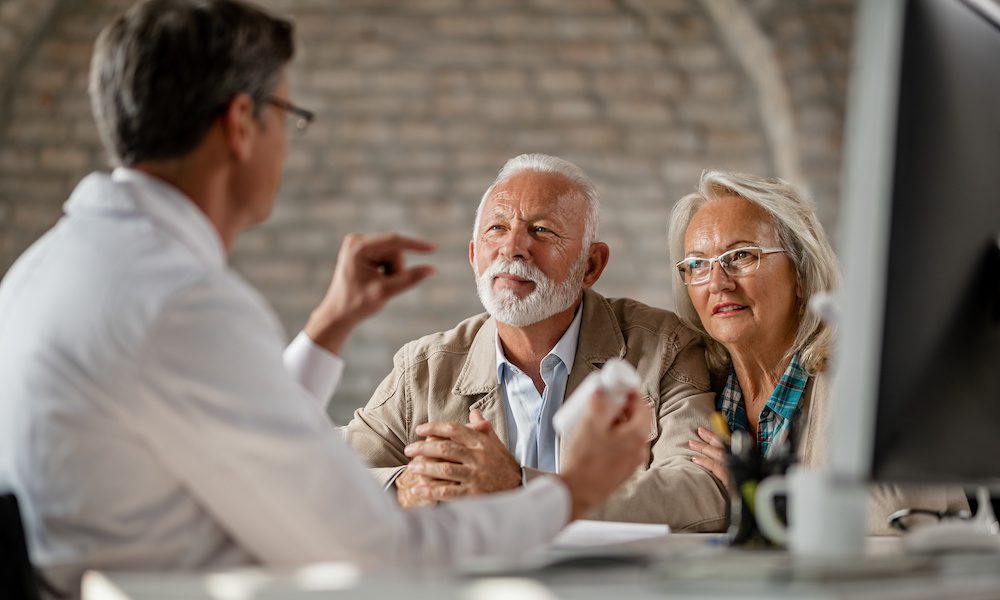 Mature couple talking to a doctor about supplement plans during a meeting.