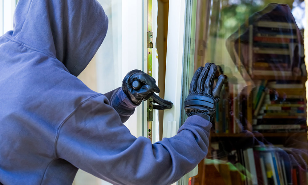 Blog - Man with Hoddie and Black Gloves Using a Crowbar to Brake Open a Window to Rob a House