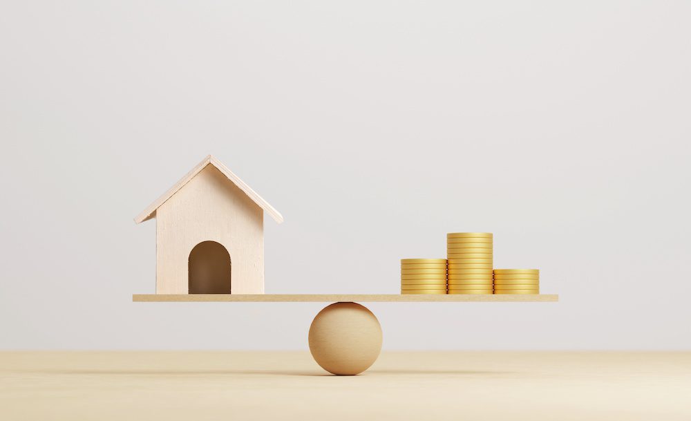 Will Inflation Increase Your Home Insurance This Year? - Wooden Home and Money Coins Stacked on Wooden Scale